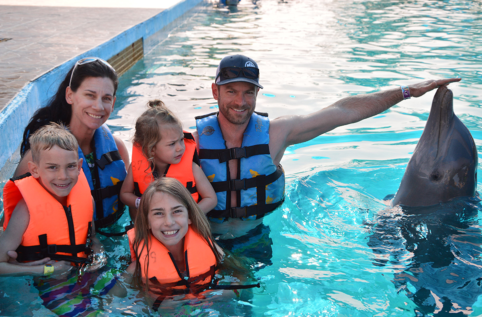 Family posing with a dolphin on vacation using their GDV travel club membership